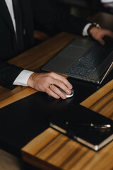 A close-up photo of a businessman working in an office at a computer, laptop, on a wooden desk. Online business concept.
