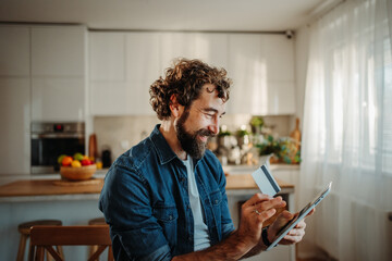 Man doing online shopping using credit card and tablet
