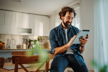 Man smiling while telecommuting with digital tablet at home