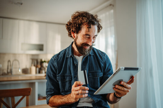 Man happy online shopping using tablet and credit card at home