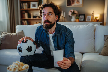 Man watching soccer game holding betting slip