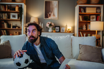 Man watching intense football match at home