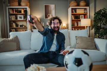 Man celebrating football win while watching tv at home