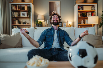 Man watching soccer match, cheering for winning team