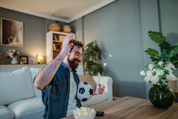 Happy man celebrating a sports betting win at home