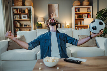 Man celebrating football goal watching game at home