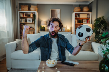 Excited man watching soccer game at home cheering goal