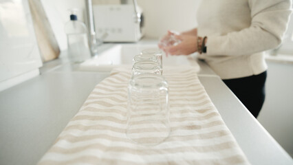 Woman Washing Glasses And Placing Them On Towel