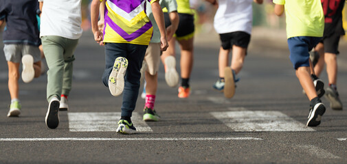 Running children, young athletes run in a kids run race,running on city road detail on legs,running in the light of morning