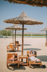 a boy and a girl were swimming in the sea and relaxing on sun beds on the beach