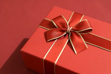 A beautifully wrapped red gift box with a golden ribbon and bow