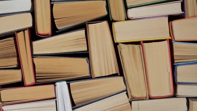 Stacked hardcover books viewed from above showing page edges and bindings, Top down composition of multiple old volumes arranged tightly as textured background
