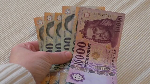 Close-up video of Hungarian forint paper banknotes waving in motion on a white background with Copy Space. Dynamic financial concept representing money flow, spending, income, inflation, cash movement