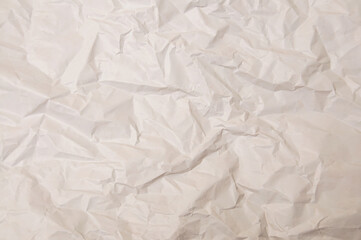 Naklejka premium Close-up texture of crumpled off-white paper with deep shadows and highlights