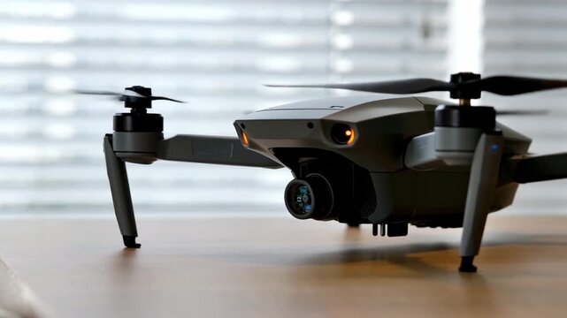 Drone quadcopter camera technology gadget flying unmanned photography videography engineering biomimicry innovation sleek modern design surveillance flight closeup detail wooden table near window