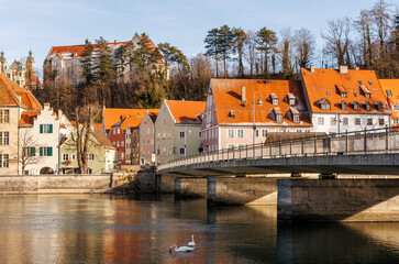 Picturesque European old town with colorful historic houses, red tiled roofs, and a stone bridge over a calm river. Scenic urban landscape with warm light, classic architecture, and tranquil atmospher
