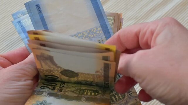 Close-up video of a female hand counting Hungarian forint banknotes on a clean white background. Strong financial concept representing income management, budgeting, salary, expenses control, accountin