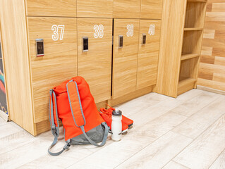 Gym locker room with backpack and training shoes, bottle of water