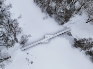 Aerial View of Snow-Covered Wooden Bridge Over Frozen Lake