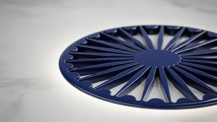 Dark blue circular trivet with a geometric radial pattern on a white marble surface. Modern kitchenware design. Copy space for text