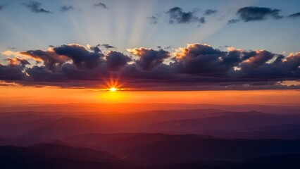Sunset over mountains dramatic rays pierce clouds vibrant hues of orange red and deep blue sky