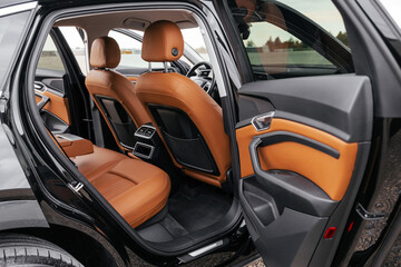 Premium, modern brown interior of an electric car, leather steering wheel, large navigation screen, air ducts, deflectors on the car panel. Interior details.
