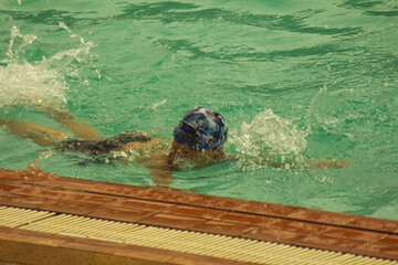 Asian child competing swimmer in the swimming pool