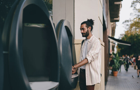 Man looks calmly at ATM screen, illustrating concentration and thoughtful interaction during secure digital banking in public self-service setting.