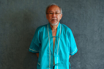Elderly man with pain and illness standing on black wall background	

