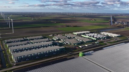 Aerial view of the sprawling AI Data Center surrounded by fields and distant wind turbines, creating a technological landscape, Middenmeer, Netherlands. - Powered by Adobe