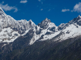 Aerial view of beautiful high altitude snow capped mountain and forest landscape