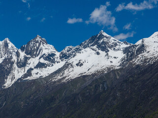 Aerial view of beautiful high altitude snow capped mountain and forest landscape