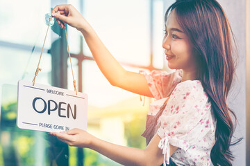 Female owner of coffee shop or restaurant turning round sign to open. Smiling young asian woman owner, employee retail coffee shop woman hand in setting sign board to open for welcome customer, reopen