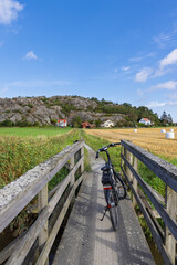 Bicycle on a wooden bridge on Tjorn island in Sweden, with rural fields and rocky hills