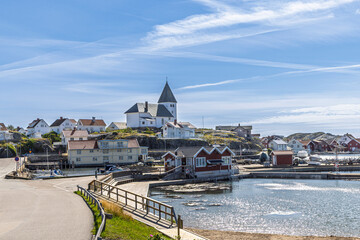 Scenic coastal village on Tjorn, Sweden with white church on hill, harbor and boats