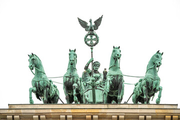 Close-up of the Quadriga sculpture with the Goddess of Victory on top of the Brandenburg Gate in Berlin, Germany, isolated against a white sky.
