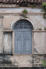 Fototapeta premium Antique Wooden Window with Ornate Carving on Weathered Stucco Wall