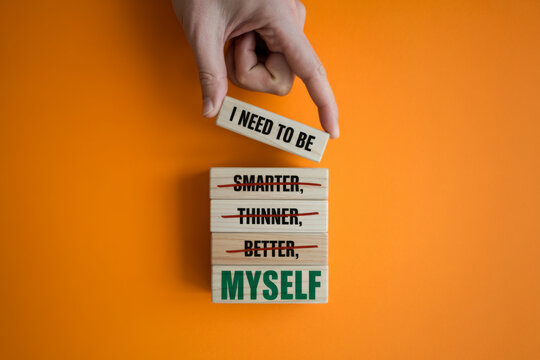Be myself symbol. Businessman hand. Wooden blocks with words 'i need to be myself, not smarter, thinner, prettier, better'. Beautiful orange background, copy space. Psychological, be myself concept.
