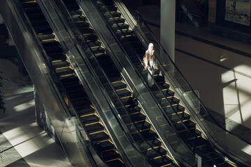 Three escalators descending in atrium, rails reflecting light and casting grid shadows, copy space