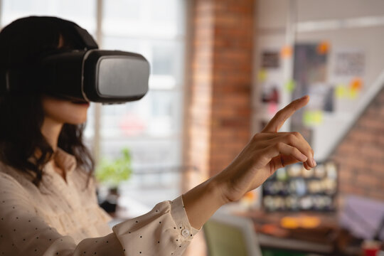 Adult woman pointing at pinboard while wearing virtual reality headset in modern office, copy space