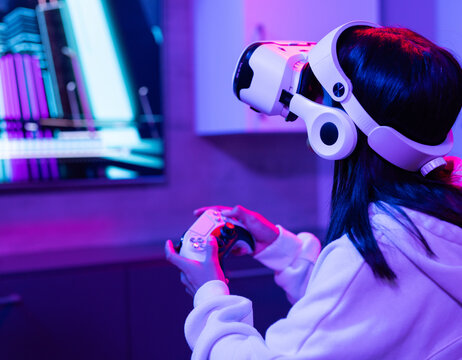 Asian woman gaming with VR headset and wireless controller in living room, copy space