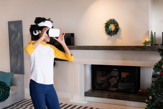 African American woman fitting virtual reality headset over eyes in living room with Christmas tree