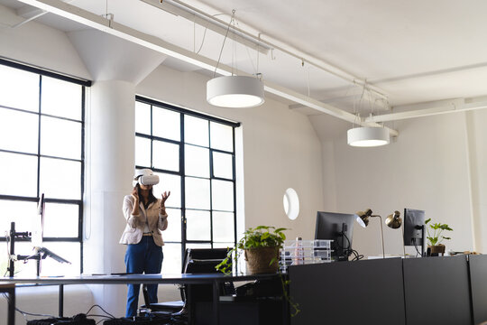 Asian female professional wearing VR headset, using interface by grid window at desk, copy space