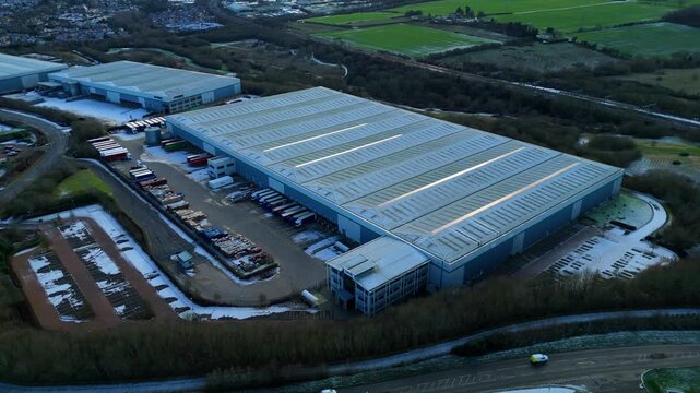 Aerial view of distribution centres with trucks and loading bays, nestled amongst green fields and roads, Kettering, Kettering, United Kingdom.