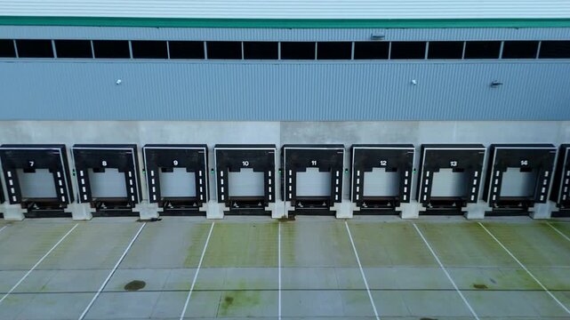 Aerial view of distribution loading bays, marked with numbers, stand in stark contrast to the wet concrete, Kettering, United Kingdom.