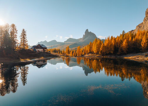 Scenic autumn view of Lago di Federa with Croda da Lago peak and cabin reflection on sunny day in Dolomites, Italy