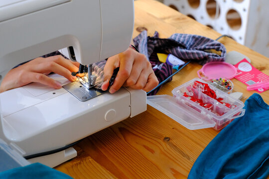 Young adult or teenager using a sewing maching for crafting and dressmaking and clothes repair.