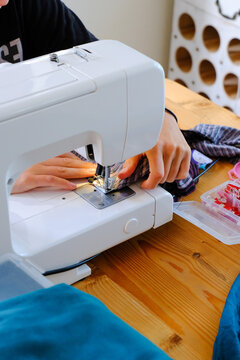 Young adult or teenager using a sewing maching for crafting and dressmaking and clothes repair.