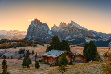 Obraz premium Scenic view of Alpe di Siusi with autumn rolling hill and rustic huts during morning in Dolomites, Italy