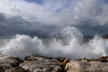 Beautiful seascape.
Background of sea waves. Stormy sea waves. Dramatic sea waves crashing against coastal rocks against a cloudy sky.